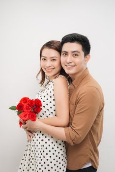 Beautiful young woman hugging her boyfriend and holding nice bouquet of red roses