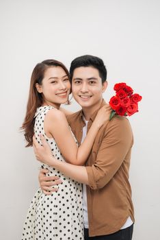 Beautiful young woman hugging her boyfriend and holding nice bouquet of red roses