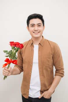 Smiling Asian man holding bunch of roses. 