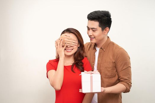  Happy young couple standing isolated over white background, celebrating, holding gift box