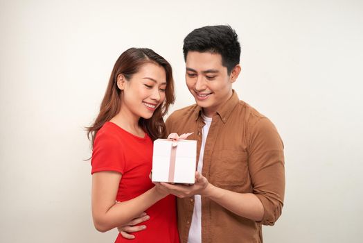 Image of excited young loving couple isolated over white wall background holding gift present box.