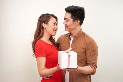 Young content couple embracing and standing with gift box having anniversary celebration