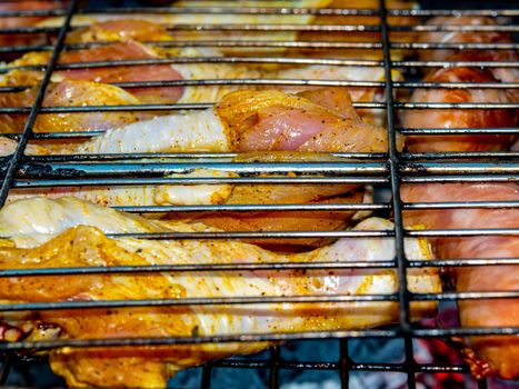 Chicken legs and meat sausages on an iron grill mesh. Cooking over a fire. Grill mesh. Chicken and meat sausages. Healthy eating. Food in nature. Menu of dishes. Background image.