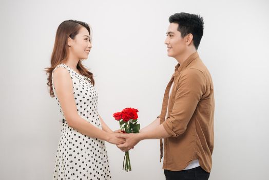 Beautiful young woman hugging her boyfriend and holding nice bouquet of red roses