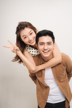 man carrying his lover on back, woman showing peace symbol over white background