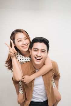 man carrying his lover on back, woman showing peace symbol over white background