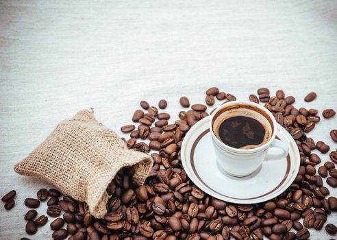 Coffee cup and beans on a biege burlap background. roasted coffee beans