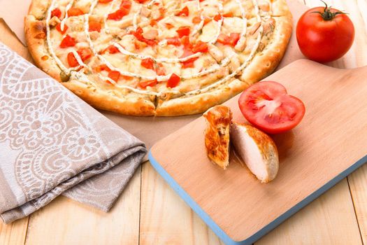 Still life of pizza with chicken and tomatoes on wooden rustic table