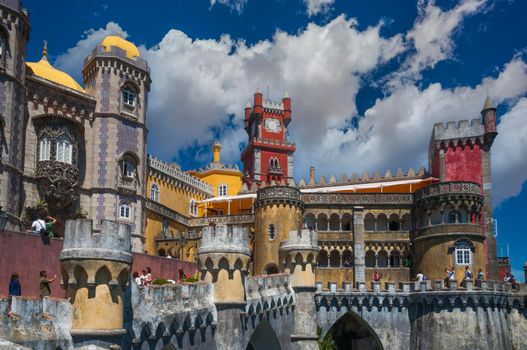 Front of the Da Pena Palace, in the Portuguese hilltop town of Sintra, with blue sky and white clouds.