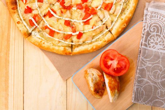 Still life of pizza with chicken and tomatoes on wooden rustic table