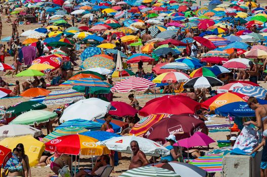 View of a beach full of people and colorful umbrellas.