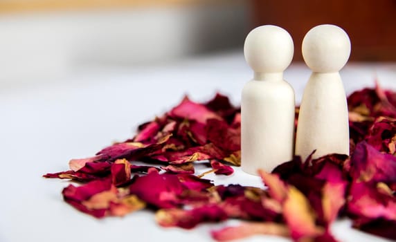 Real love, lover, couple concept. Two wooden figures with red rose petals on white background, standing together isolated on white background. copy space space for text