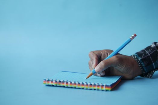 man hand writing on notepad while sited ,