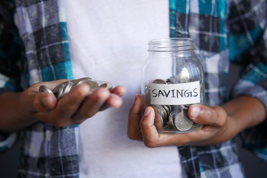 young man saving coins in a jar white sited .