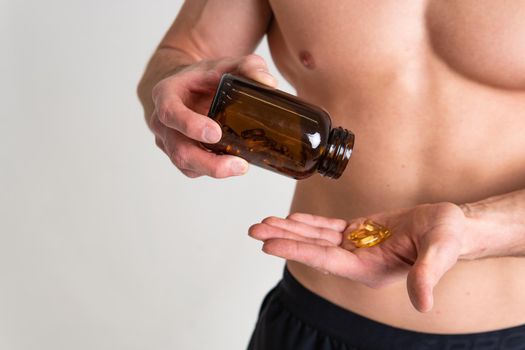 Fish oil is eaten by a man in the hands of vials and a glass bottle pill health vitamin, diet tablet caucasian. Remedy translucent, background female giving dieting