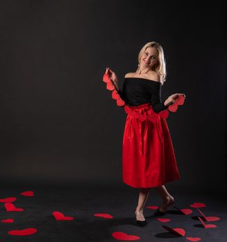 Girl holding a garland of Valentine's heart, valentine's design, on the floor hearts are a beautiful layout. inspiration is art. event forever, joy in a red dress girl, barefoot