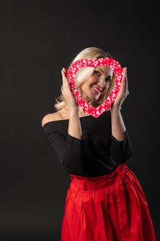 Girl holds a heart at eye level love red, heart, on the floor hearts romance . February 14 . day formula of love, joy in a red dress girl, barefoot