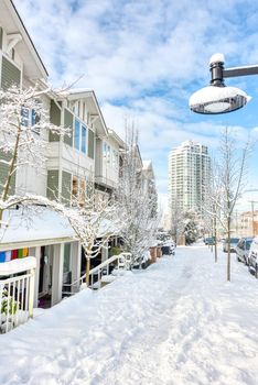 Residential townhouses and high-rise apartment building on bright winter day and cloudy sky background