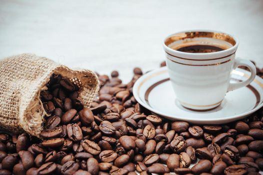 Coffee cup and beans on a biege burlap background. roasted coffee beans