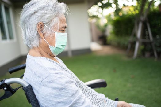 Asian senior or elderly old lady woman on wheelchair and wearing a face mask for protect safety infection Covid-19 Coronavirus in park.