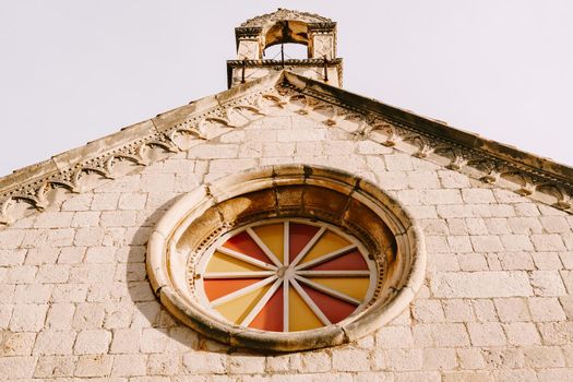 Rose window with multicolored glass on the stone wall of the church. High quality photo