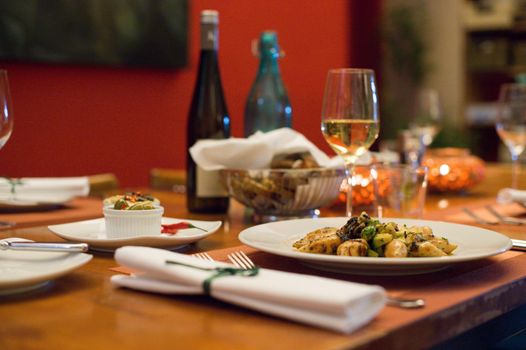 A wooden restaurant table is elegantly set and grilled calamari are ready to be eaten on a plate.