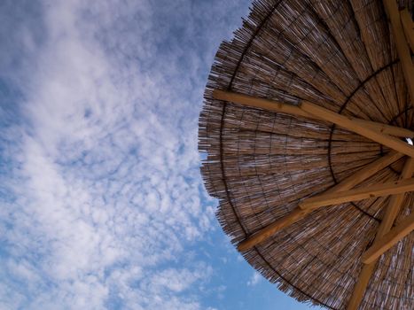 Part of the straw beach umbrellas and View of the beautiful blue sky with little clouds