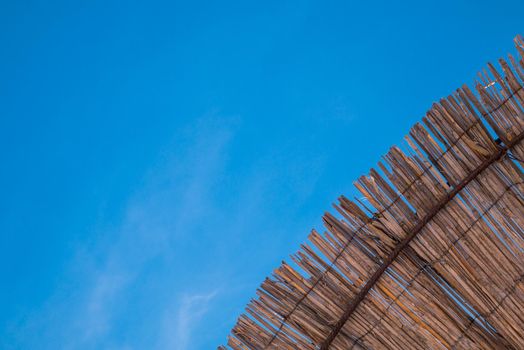 Part of the straw beach umbrellas and View of the beautiful blue sky with little clouds