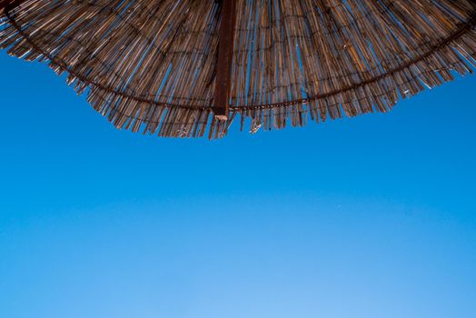 Part of the straw beach umbrellas and View of the beautiful blue sky with little clouds