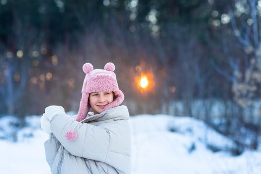 Cute little teenage girl having fun playing with snowballs, ready to throw the snowball. Snow games. Winter vacation.