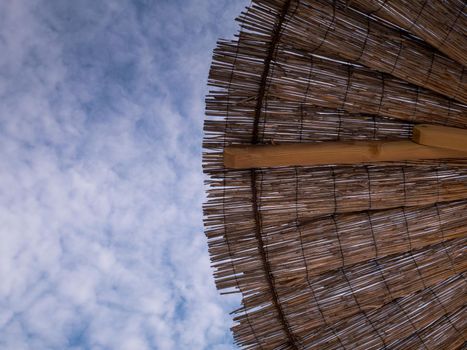 Part of the straw beach umbrellas and View of the beautiful blue sky with little clouds