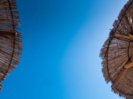 Part of the straw beach umbrellas and View of the beautiful blue sky with little clouds