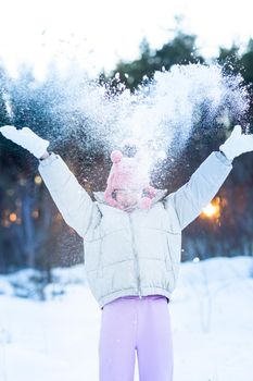 Cute little teenage girl having fun playing with snowballs, ready to throw the snowball. Snow games. Winter vacation.