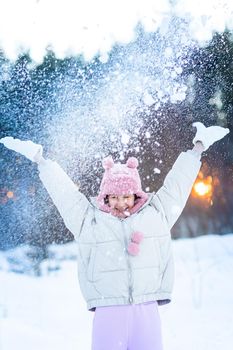 Cute little teenage girl having fun playing with snowballs, ready to throw the snowball. Snow games. Winter vacation.