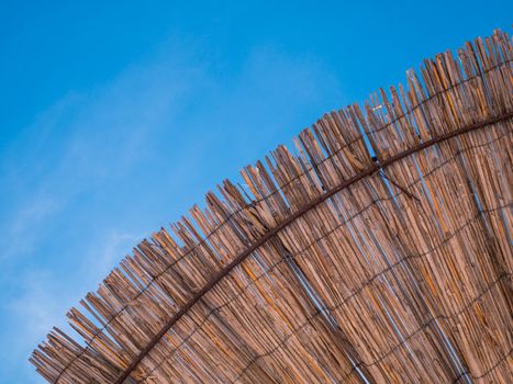 Part of the straw beach umbrellas and View of the beautiful blue sky with little clouds