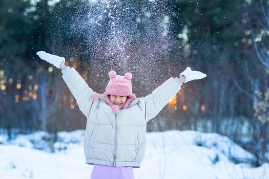 Cute little teenage girl having fun playing with snowballs, ready to throw the snowball. Snow games. Winter vacation.