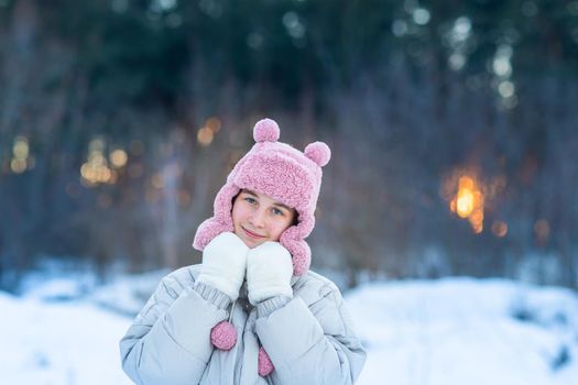 Cute little teenage girl having fun playing with snowballs, ready to throw the snowball. Snow games. Winter vacation.