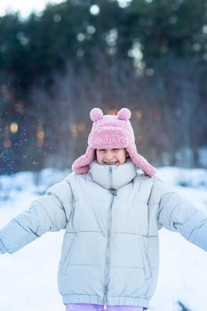 Cute little teenage girl having fun playing with snowballs, ready to throw the snowball. Snow games. Winter vacation.