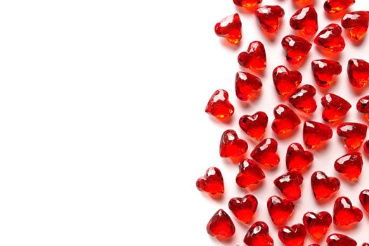 Directly Above Studio Full Frame Image of Sparkling Red Faux Gemstone Hearts on a White Studio Background. Gemstone Hearts are clustered on the Right with White Copy Space on the Left