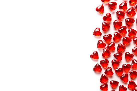 Directly Above Studio Full Frame Image of Sparkling Red Faux Gemstone Hearts on a White Studio Background. Gemstone Hearts are clustered on the Right with White Copy Space on the Left