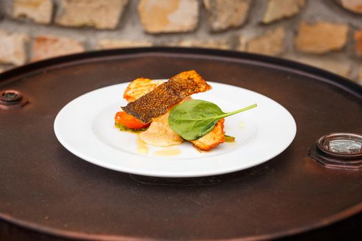 Salmon steak with creamy sauce and vegetables on white plate