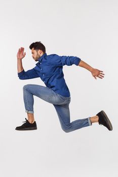 An attractive athletic businessman jumping up against white background.