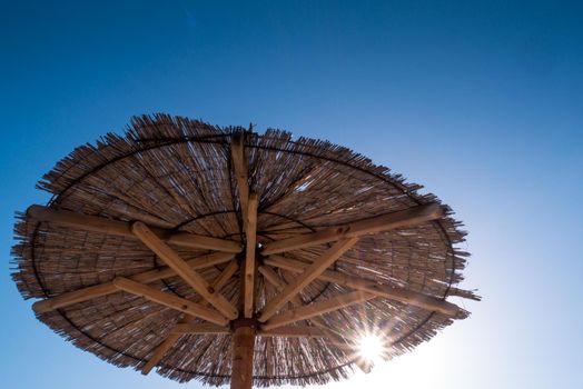 Beach umbrella, view of the beautiful blue sky and straw beach umbrella. Perfect holiday concept. Travel and vacation. Beach on Vir Island, Croatia, Europa. Copy space.