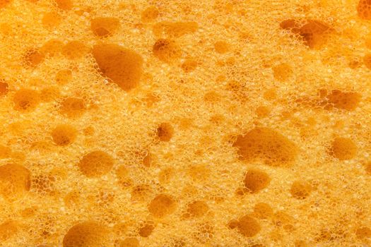 Foam sponge texture in macro. Textured background. Dishwashing or car cleaning concept. Abstract yellow wallpaper or backdrop for your design closeup