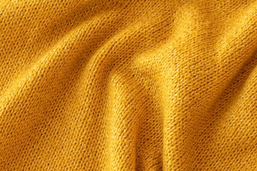 Soft knitted yellow sweater texture closeup. Light orange abstract background. Trendy soft mustard-colored backdrop for web design. Luxury twisted fabric backplate