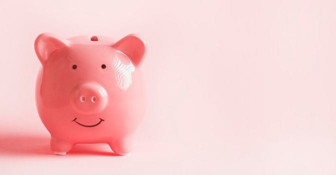 Piggy bank in the form of a smiling pink pig to save wealth, savings and financial success, close-up view.