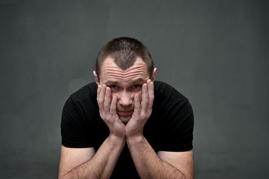 portrait of a large man man on a gray background looking at the camera in despair