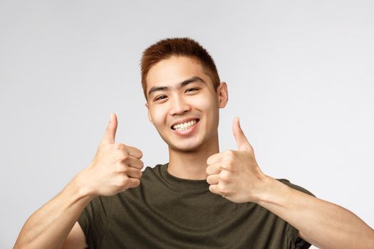 People, different expressions and lifestyle concept. Close-up portrait of happy, satisfied asian man leave positive review, show thumbs-up in approval, recommend product, like and agree.