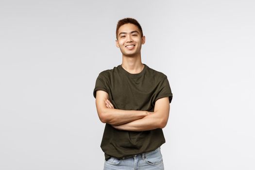 Good-looking taiwanese guy, teenage college student male, cross arms chest smiling proud and satisfied, show-off his ego, standing studio background satisfied and cheerful.