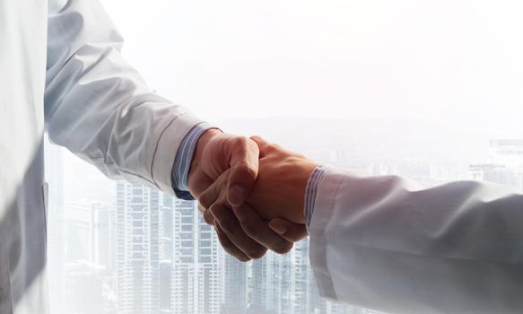 Close-up of the handshake between the two medics. Against the backdrop of the cityscape